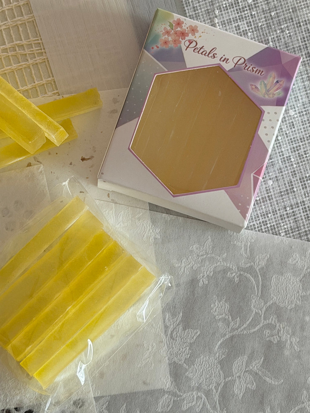Yellow crystal candy prisms beside a Petals in Prism gift box